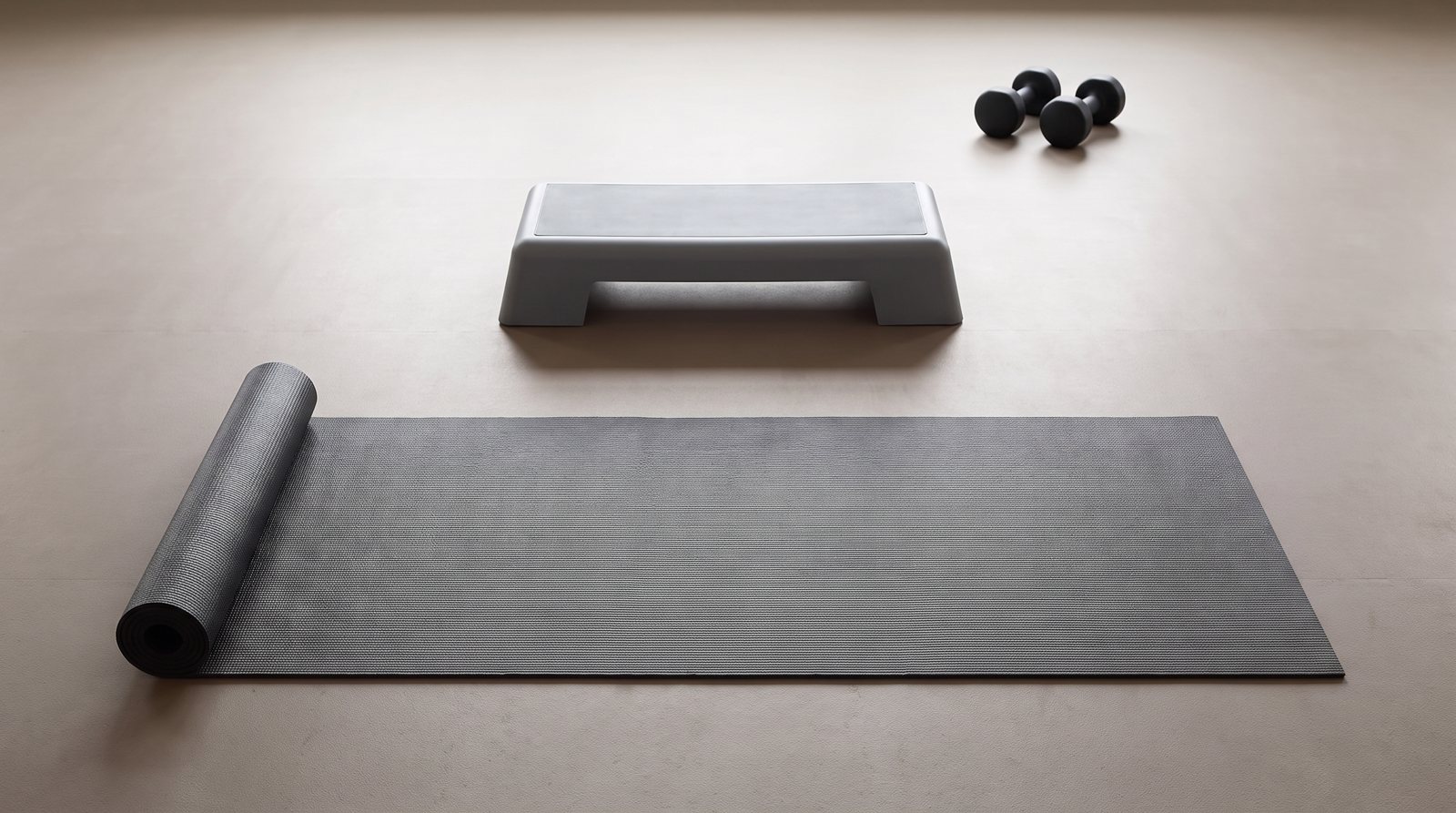 A mat, low step and unmarked dumbbells arranged in separate workout spaces.