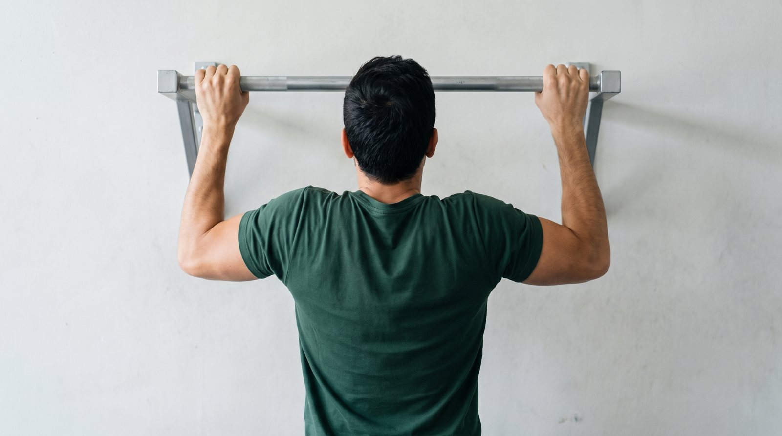 Rear view of an adult holding a pull-up bar with bent elbows.