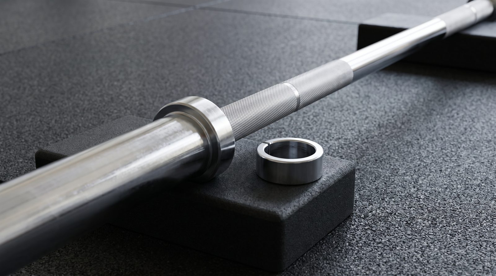 An empty barbell sleeve and knurled shaft with a separate collar on rubber blocks.