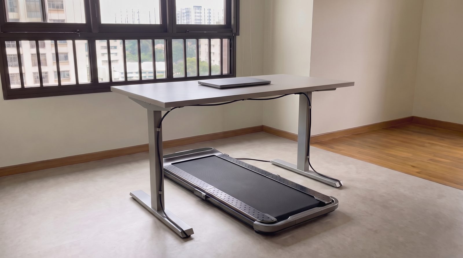 An under-desk walking pad with a standing desk and closed plain laptop.