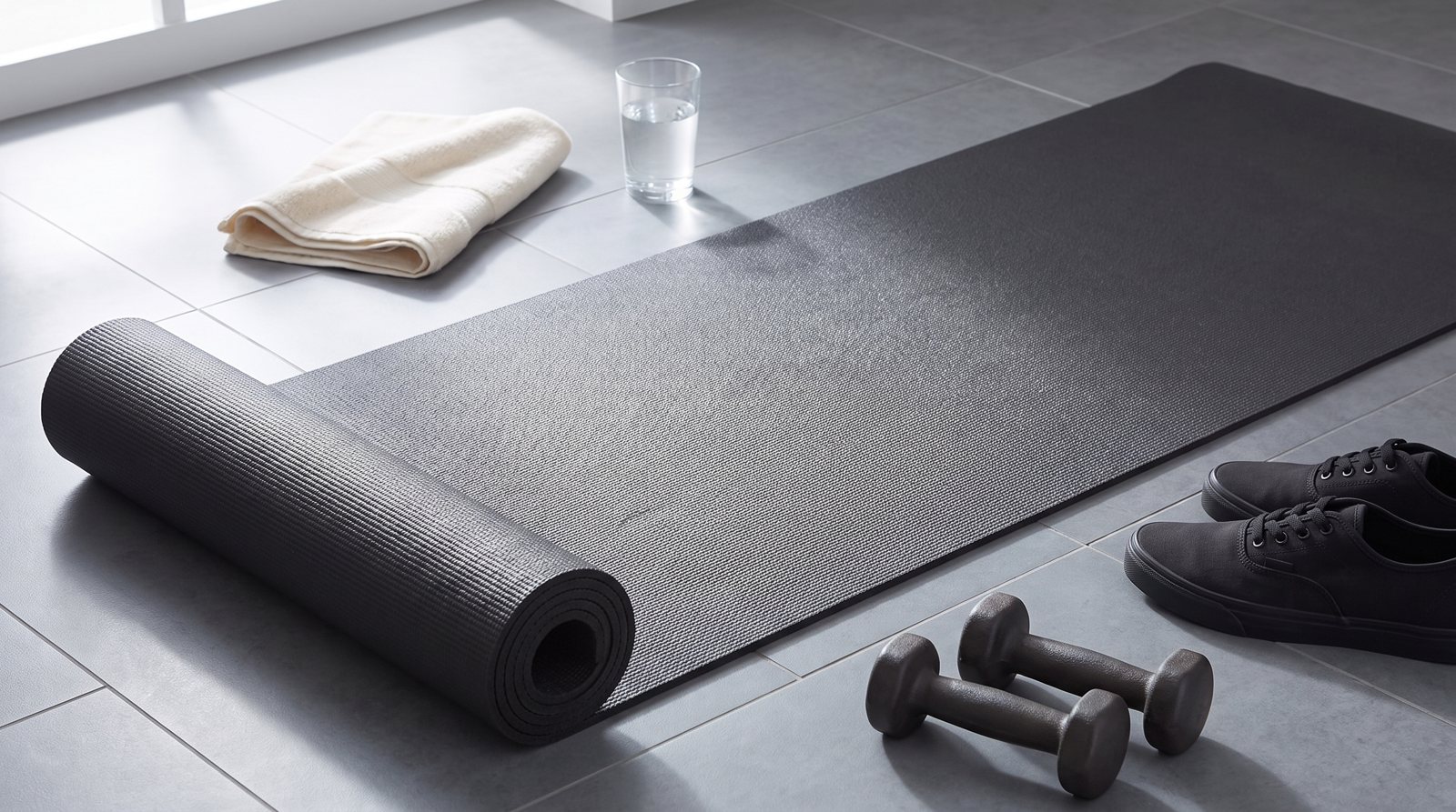 A textured exercise mat with a towel and water set beside it.