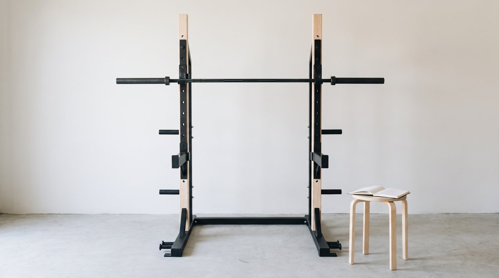An empty squat rack with an unloaded bar and blank training notebook.