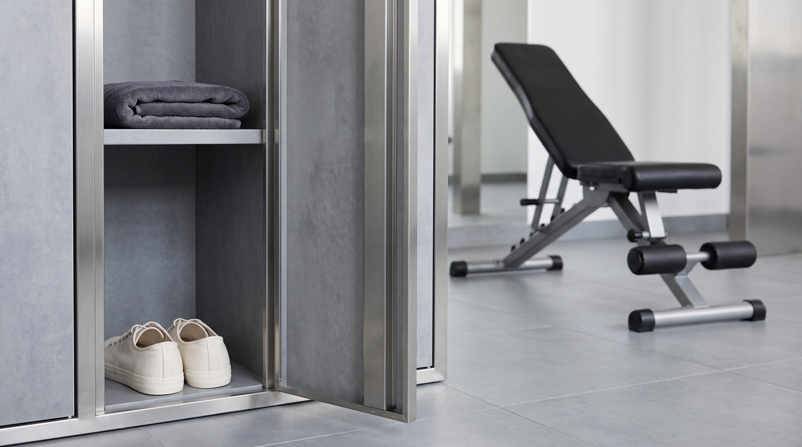 An open locker with basic training kit and an empty exercise station beyond.