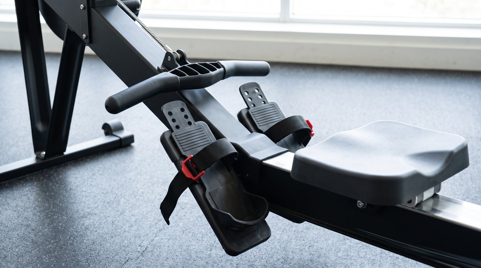 A rowing machine handle, foot straps and seat prepared for setup.