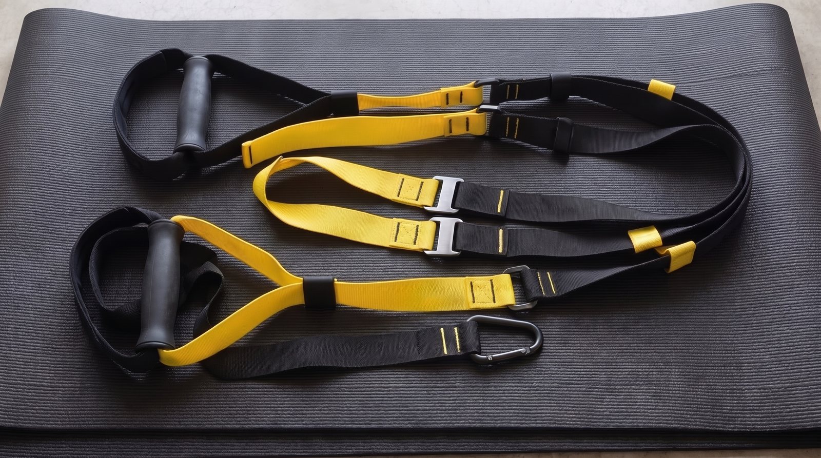 Uninstalled suspension-training straps with handles, foot cradles and adjustment buckles.