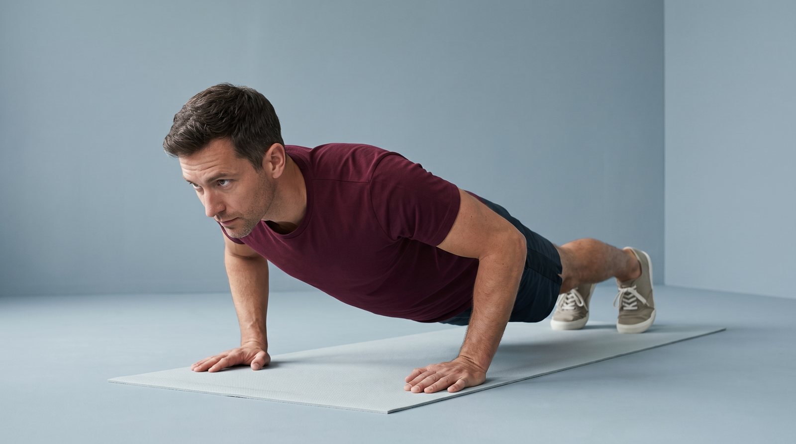An adult in a lowered push-up position on a mat.